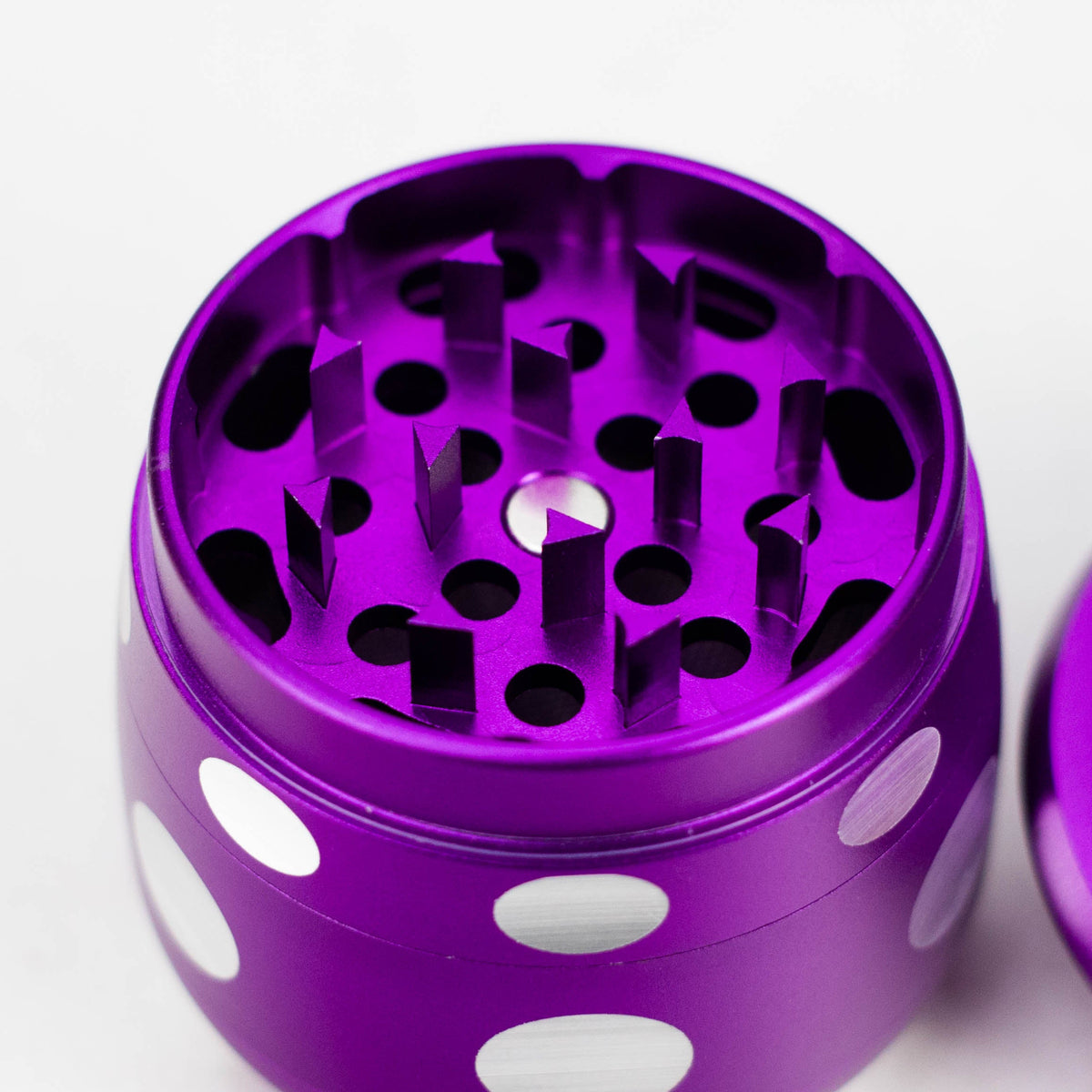 Close-up of diamond-shaped teeth and magnet inside the purple mushroom herb grinder