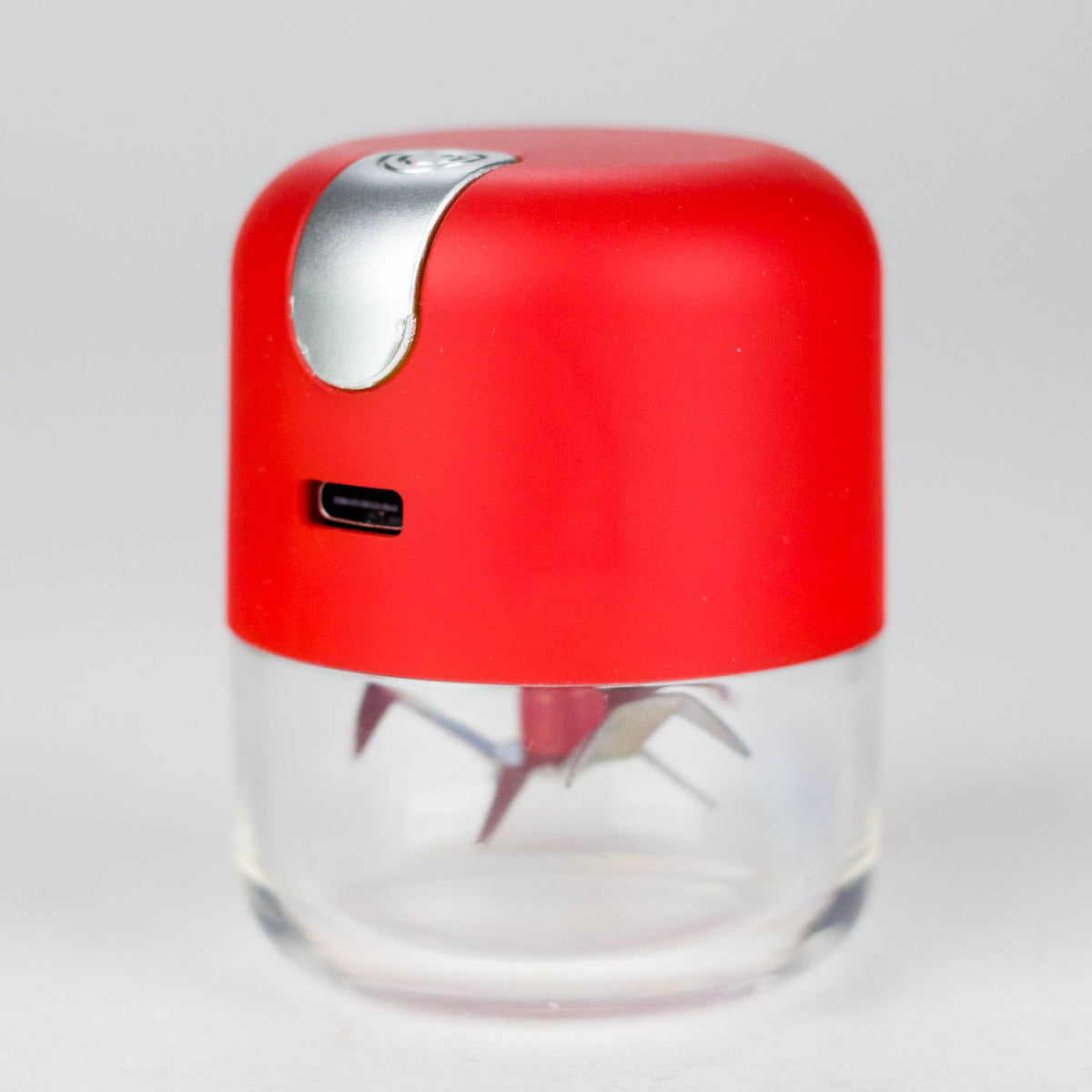 Angled Red electric grinder view showing the USB charging port, silver button and blades through the clear chamber