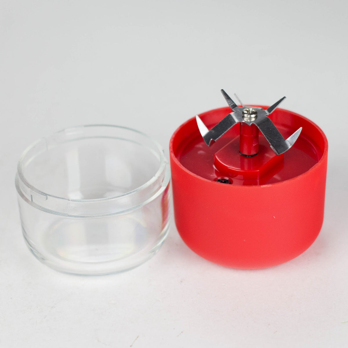 Red electric grinder opened to show the metal blades beside the detached clear chamber